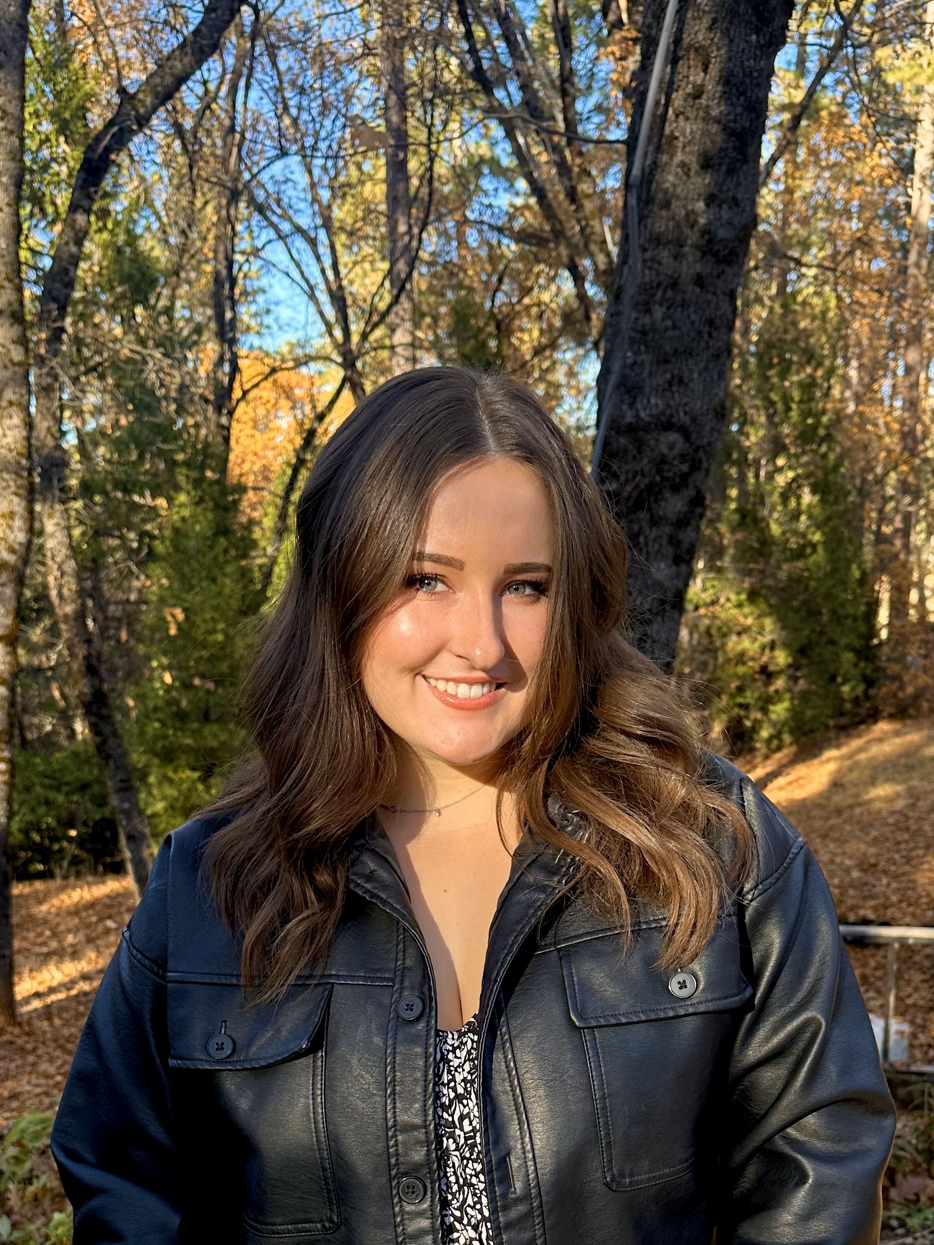 Madison Pelland in front of trees smiling.
