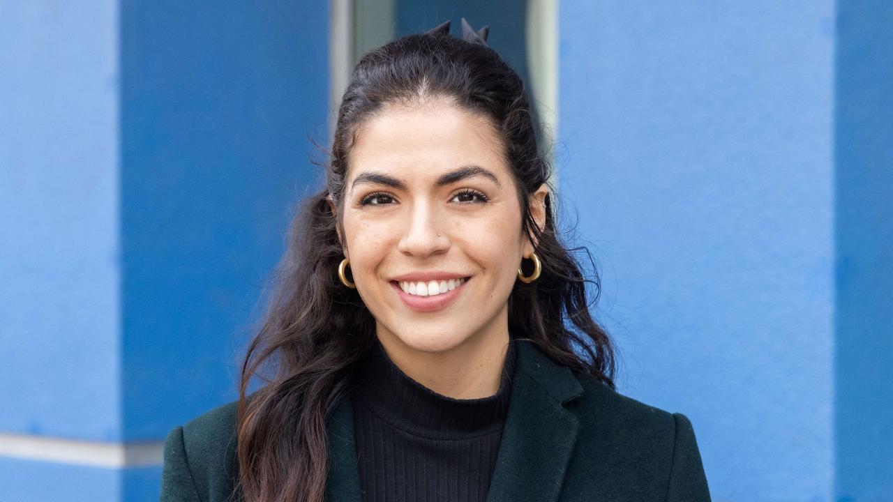 Erin Rodriguez featured smiling in front of a blue wall.