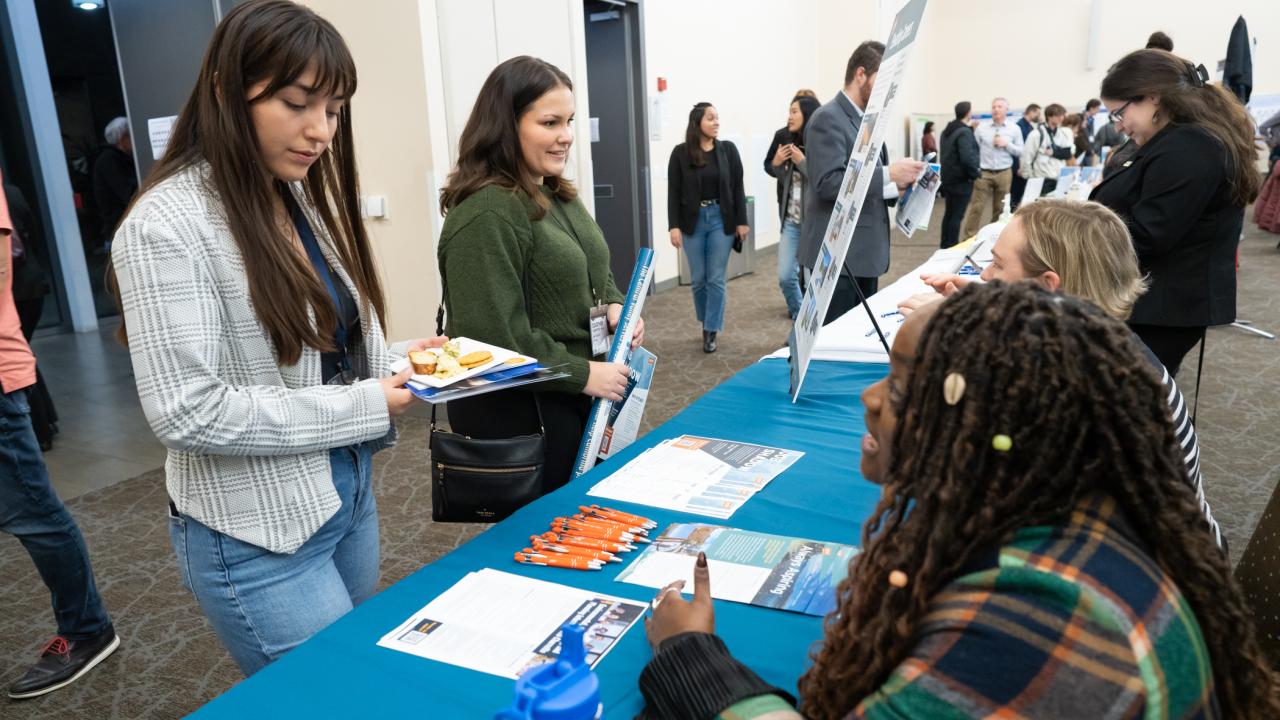 Two students are speaking with employees from Ascent Environmental.