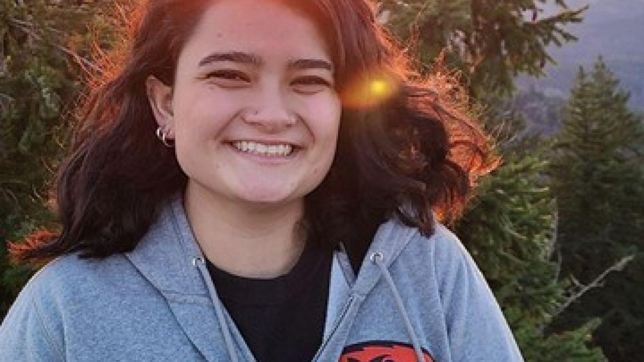 Julia Jamison smiling in front of a tree and the sunset.