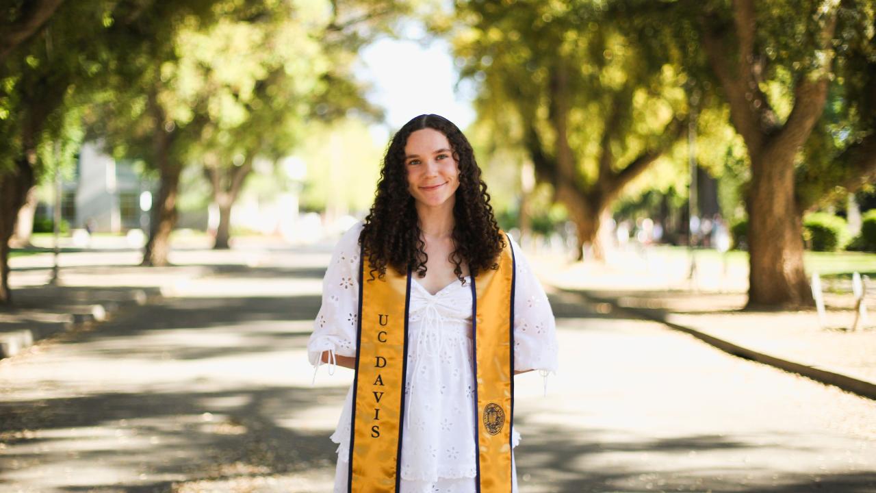 Morgan Hickey featured standing in front of trees and a stole for her graduation from UC Davis.