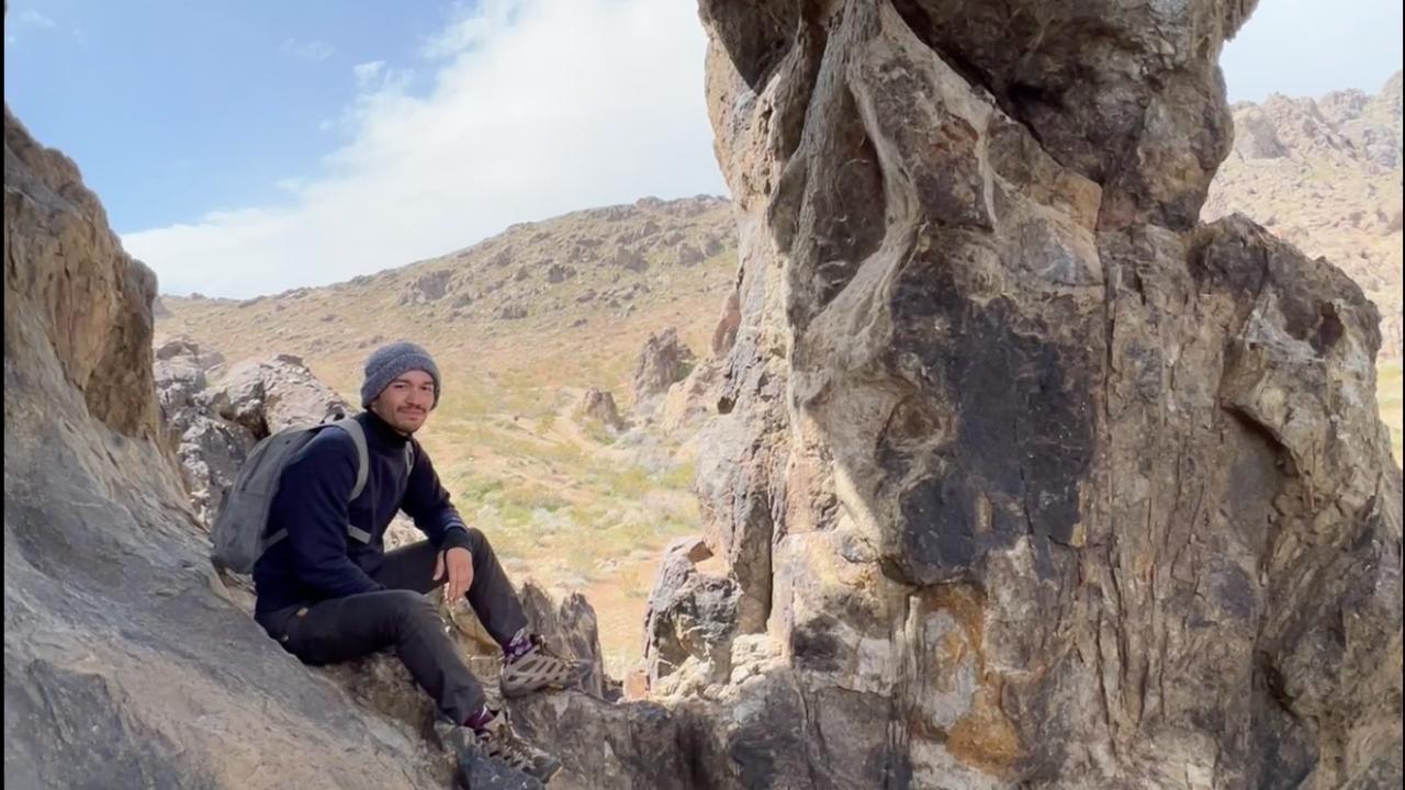 Daniel Harper sitting in a rock formation near Barstow, CA