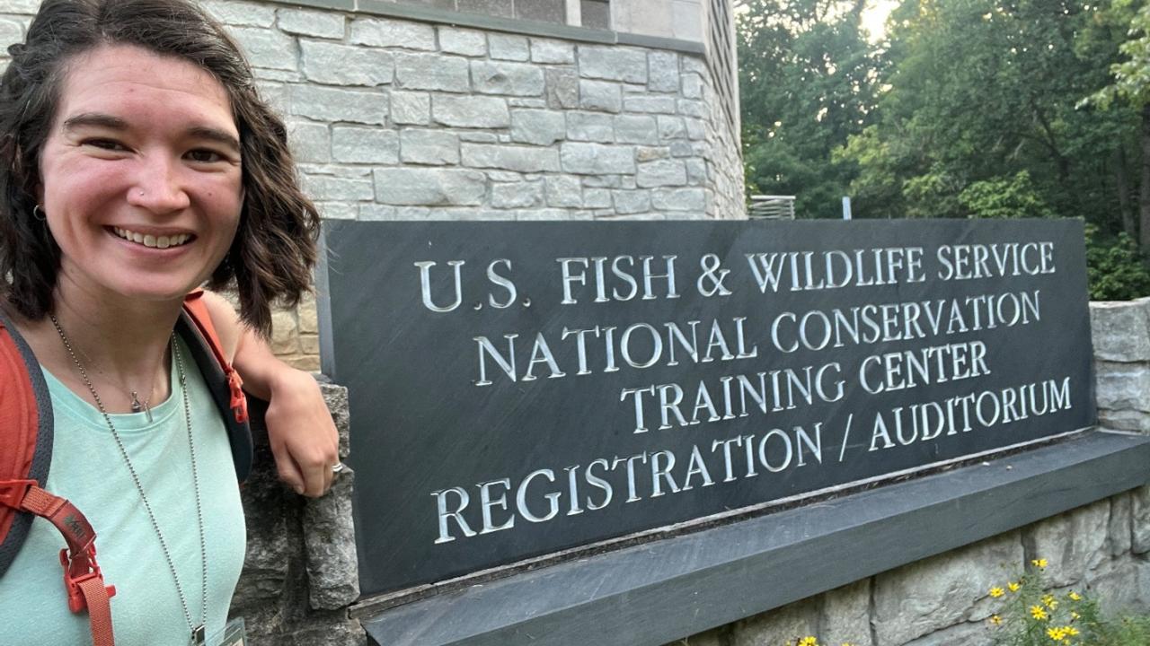 Amanda Specht smiling in front of a US Fish and Wildlife Service sign