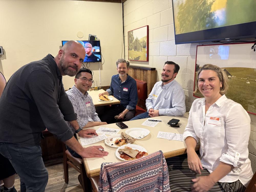 A group of folks sitting at a table filling out a bingo card.