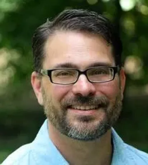 Michael McCormick featured in front of greenery smiling.