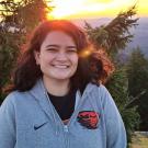 Julia Jamison smiling in front of a tree and the sunset. 