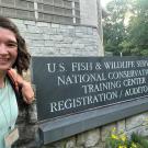 Amanda Specht smiling in front of a US Fish and Wildlife Service sign