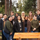 EPM students at Apple Hill, standing in front of trees and a wooden table.