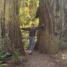 Kaitlyn Finlayson smiling in the middle of two large trees.